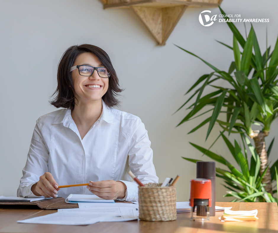 Woman sitting at desk with plants around her.