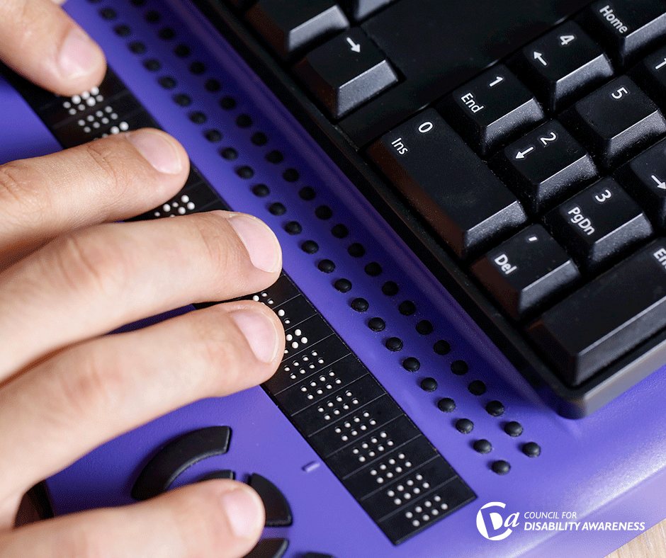 Blind person using computer with braille computer display and a computer keyboard.